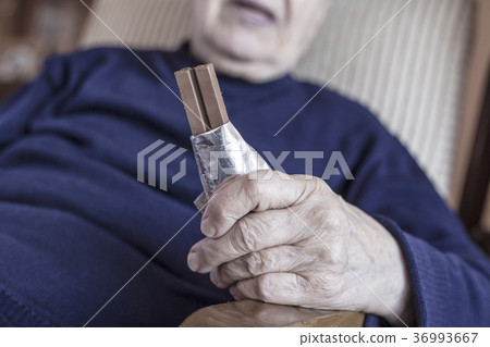 hand of a senior person holding a chocolate bar 36993667