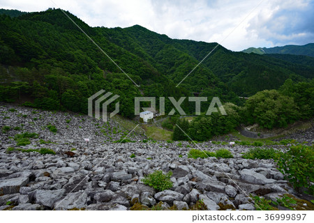 Kotogawa Dam in the fresh greenery: A beautiful early summer landscape woven from the magnificent rock-fill dam and lush mountains. Kotogawa Dam in the fresh greenery: A beautiful early summer landscape woven from the magnificent rock-fill dam and lush mountains. 36999897