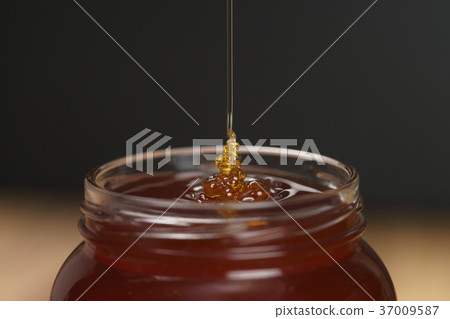 pour honey into glass jar closeup pour honey into glass jar closeup 37009587