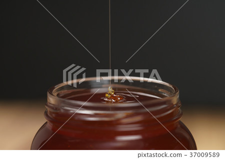 pour honey into glass jar closeup pour honey into glass jar closeup 37009589