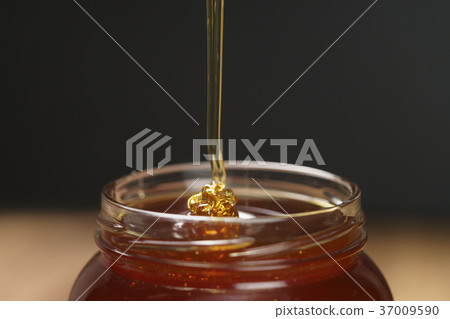 pour honey into glass jar closeup pour honey into glass jar closeup 37009590