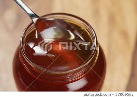 scooping organic honey with spoon from glass jar scooping organic honey with spoon from glass jar 37009592