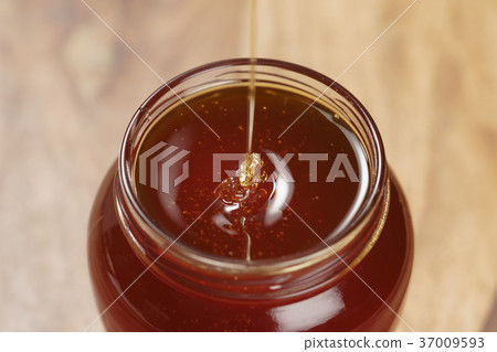 pour honey into glass jar closeup pour honey into glass jar closeup 37009593