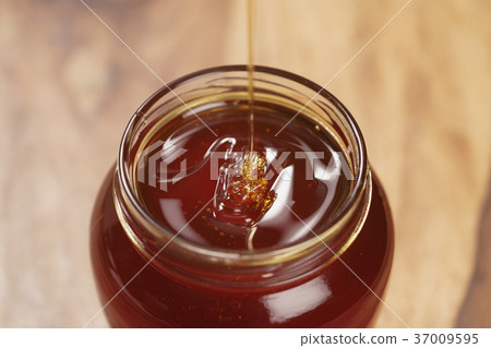 pour honey into glass jar closeup pour honey into glass jar closeup 37009595