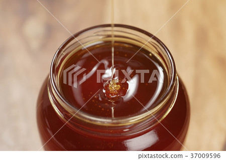 pour honey into glass jar closeup pour honey into glass jar closeup 37009596