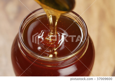 pouring organic honey from spoon into glass jar pouring organic honey from spoon into glass jar 37009600