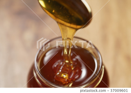 pouring organic honey from spoon into glass jar pouring organic honey from spoon into glass jar 37009601