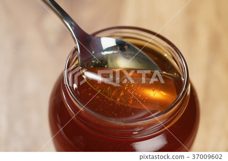scooping organic honey with spoon from glass jar scooping organic honey with spoon from glass jar 37009602