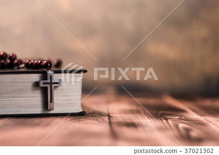 Bible and the crucifix on a wooden dark table.  Bible and the crucifix on a wooden dark table.  37021302