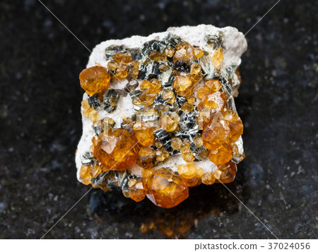 raw crystals of spessartine gemstone on dark 37024056
