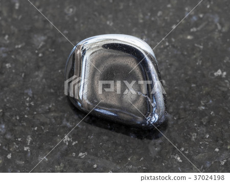 tumbled hematite gem on dark granite background 37024198