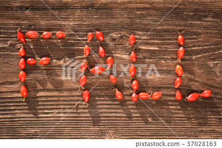 Word FALL made of wild rose hips on  wooden table 37028163
