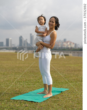 Asian chinese woman practising yoga outdoors with young baby gir Asian chinese woman practising yoga outdoors with young baby gir 37032892