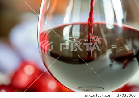 Pouring red wine into the glass against grape Pouring red wine into the glass against grape 37033066