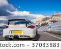 Rear shot of a high-end sports car on the foot of a snowy mountain in spring 37033883