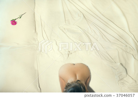 Beautiful naked female sits on the bed.  37046057