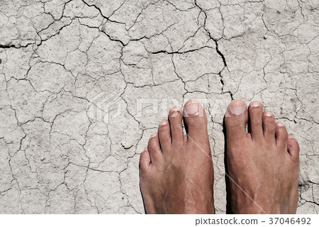 bare feet of a man on a cracked dry soil 37046492