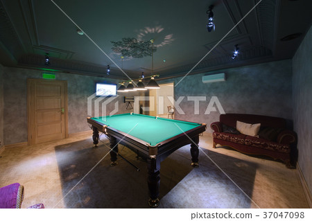 A table for billiards, a dark sofa and the TV in t 37047098