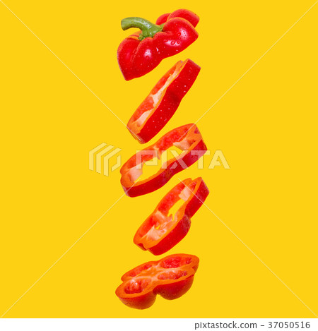 Creative concept with flying red capsicum. Sliced floating bell pepper on an orange background 37050516