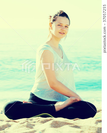 Smiling adult woman in white T-shirt is practicing stretching 37057255