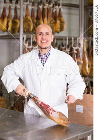 Mature butcher slicing jamon at store. 37057316