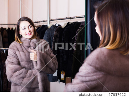 woman trying on fur coat in women’s cloths store 37057622