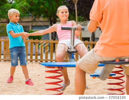 kids are teetering on the swing on the playground. kids are teetering on the swing on the playground. 37058195