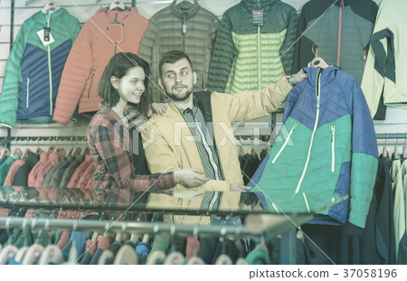 Guy and the girl are watching the choice of jackets 37058196