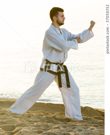 man practising karate poses at seaside 37058352