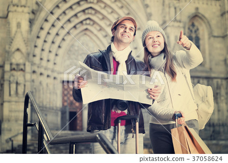 Man and woman with map and package looking attraction outdoors Man and woman with map and package looking attraction outdoors 37058624
