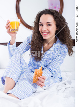 Female brunette with pastry and juice in bed Female brunette with pastry and juice in bed 37058873