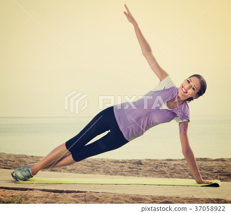 Woman doing exercises on beach by ocean Woman doing exercises on beach by ocean 37058922