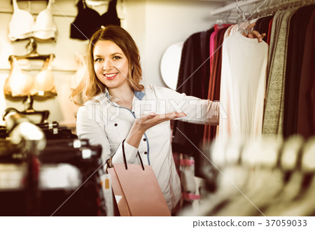 Female customer deciding on pretty long sleeve shirt Female customer deciding on pretty long sleeve shirt 37059033