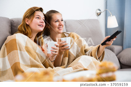 Girlfriends are watching TV and drfinking tea 37059159
