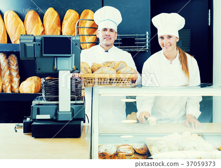 Male and female staff offering fresh baguettes Male and female staff offering fresh baguettes 37059373