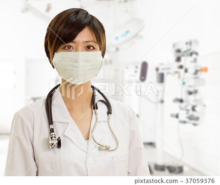 Asian female doctor with surgical mask looking at camera in clin Asian female doctor with surgical mask looking at camera in clin 37059376