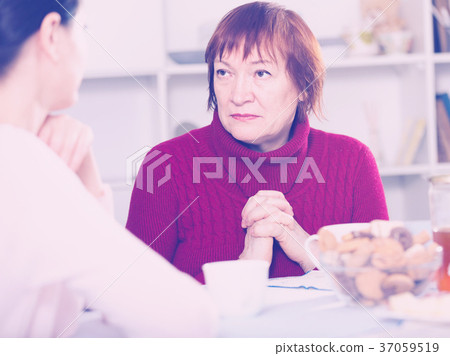 Unhappy adult female talking with daughter at table Unhappy adult female talking with daughter at table 37059519