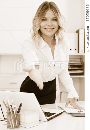 Kindly girl with an outstretched hand is standing near table 37059686
