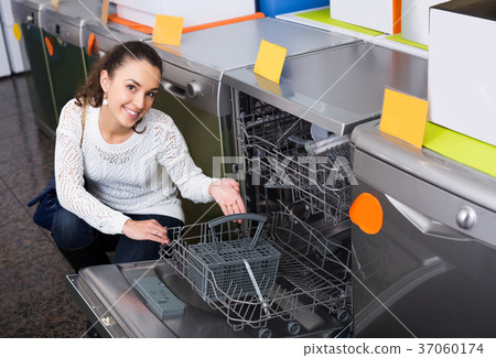 Happy brunette choosing new dish washing machine in appliance store 37060174