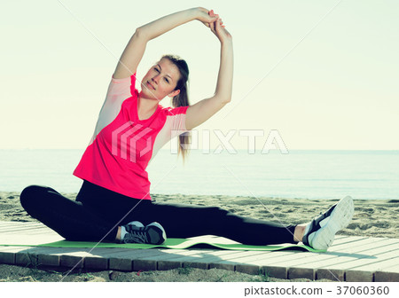 Woman exercising yoga poses on beach Woman exercising yoga poses on beach 37060360