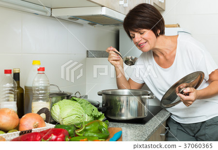 mature woman kitchen soup 37060365