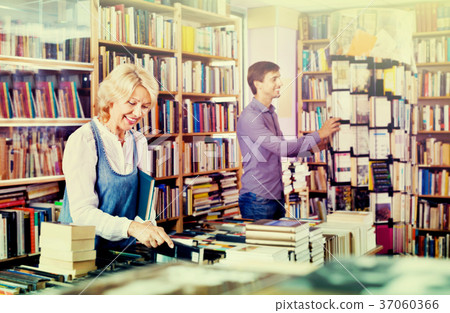 Mature smiling woman picking new book 37060366