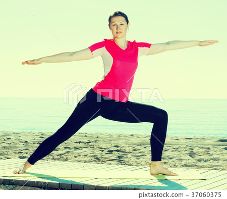 Girl practicing yoga poses on beach 37060375