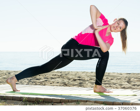 Woman exercising yoga poses on beach 37060376