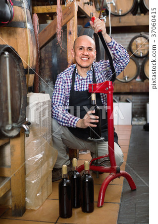 Mature male wine maker corking bottle of wine Mature male wine maker corking bottle of wine 37060415