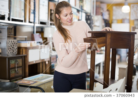 Positive woman customer choosing bedside in shop 37060943