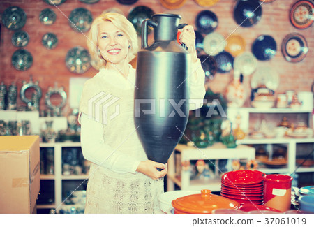 Smiling mature female holding ceramic crockery Smiling mature female holding ceramic crockery 37061019