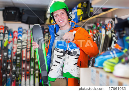 Customer male in ski equipment showing ski and boots 37061083