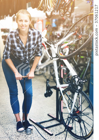 Female master is standing with pump for bicycle Female master is standing with pump for bicycle 37061217