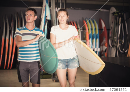 Couple with surfing boards standing in store 37061251